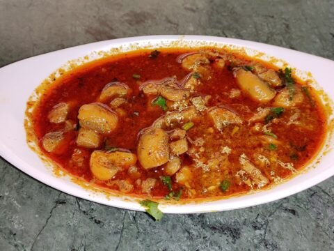 Kaalan - spicy roadside-style mushroom curry in thick reddish gravy with coriander garnish