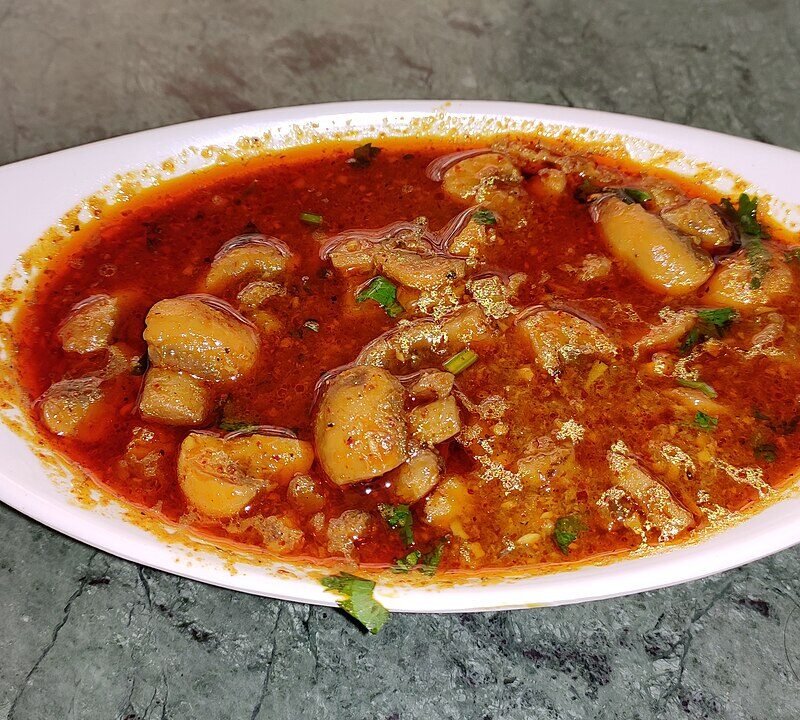 Kaalan - spicy roadside-style mushroom curry in thick reddish gravy with coriander garnish