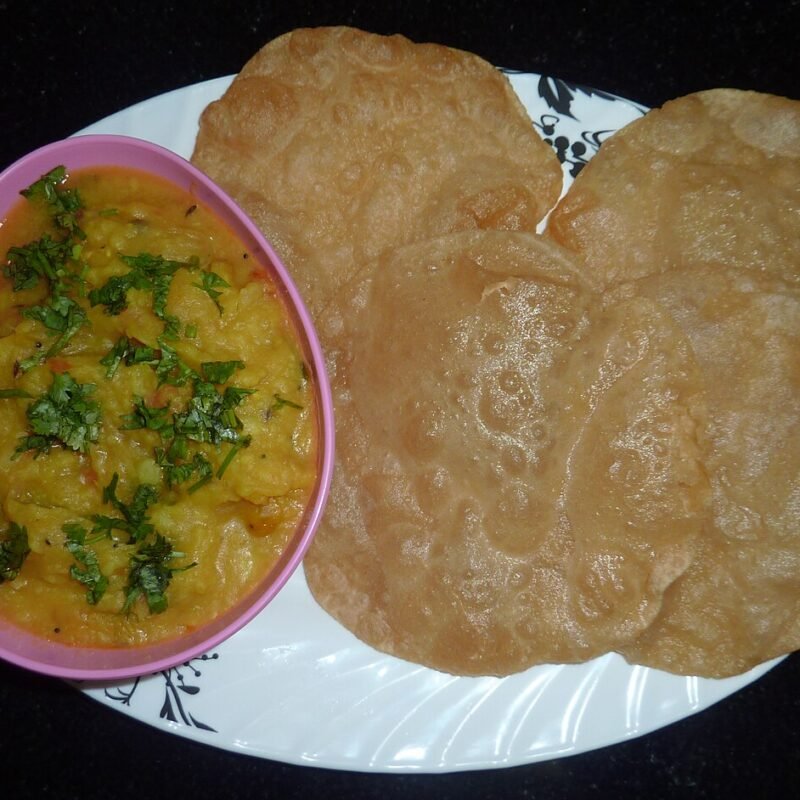 Puffed golden poori served with potato masala
